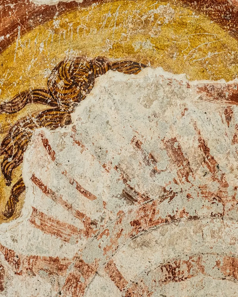 Detalle de un fresco antiguo con una figura de tonos terrosos y ocres sobre fondo desgastado